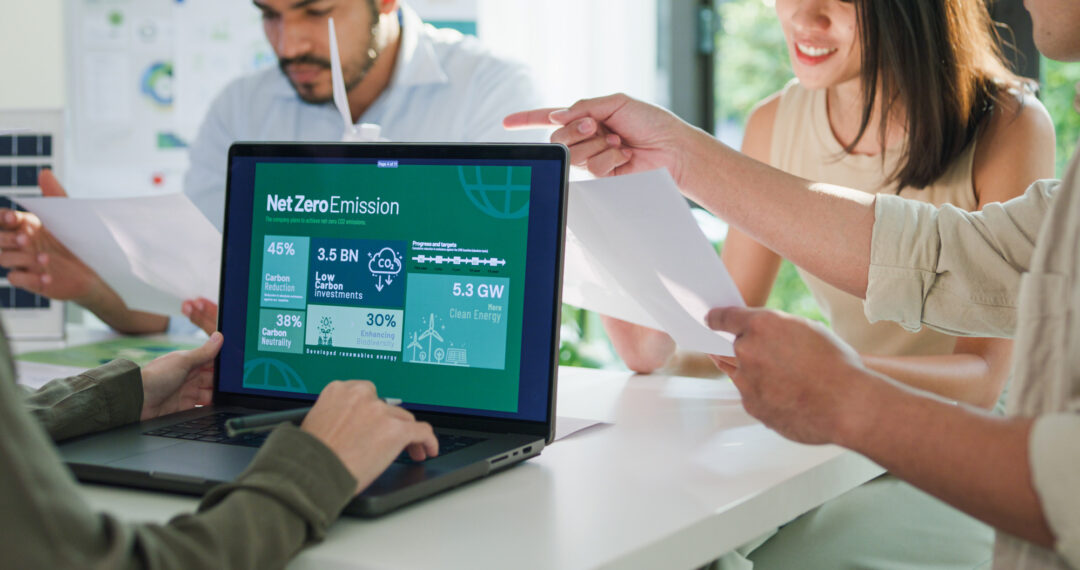 Eine Arbeitsgruppe mit Laptop mit geöffnetem Nachhaltigkeitsbericht